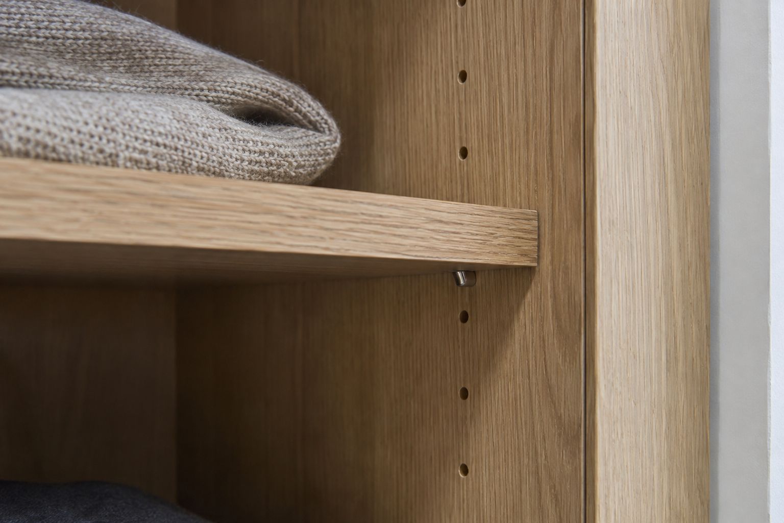 Design visualization: Oak shelf resting on a small metal pin within an adjustable closet panel