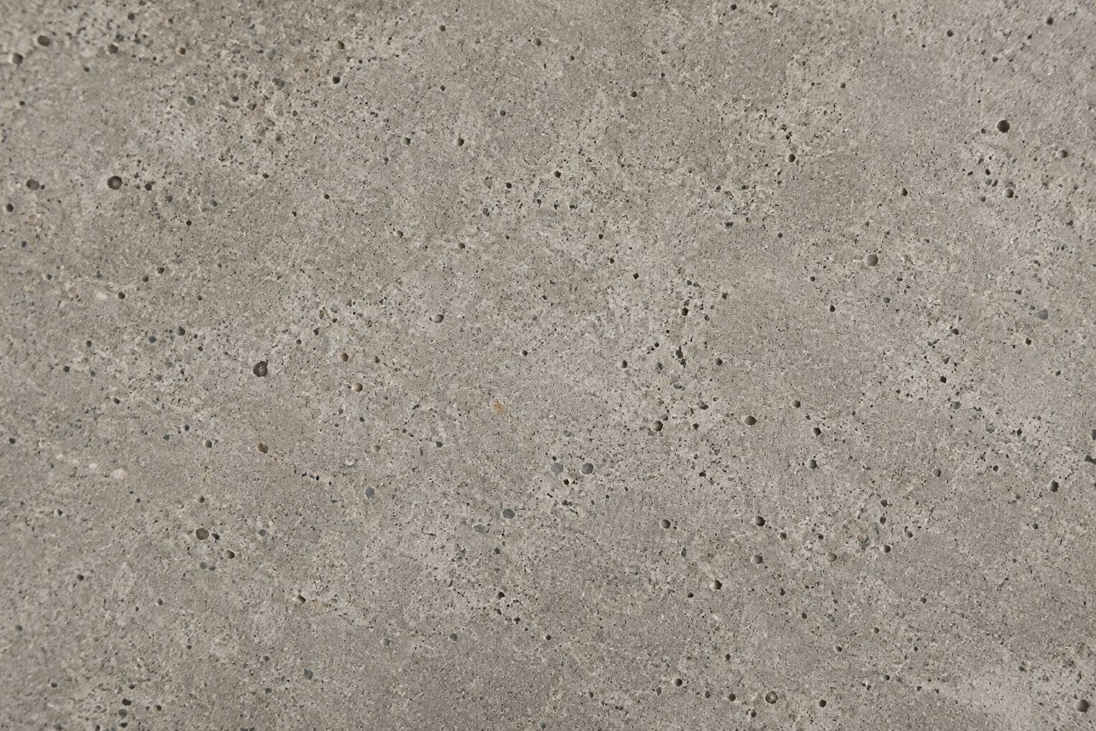 Honed warm-gray concrete with fine aggregate and small natural surface pores