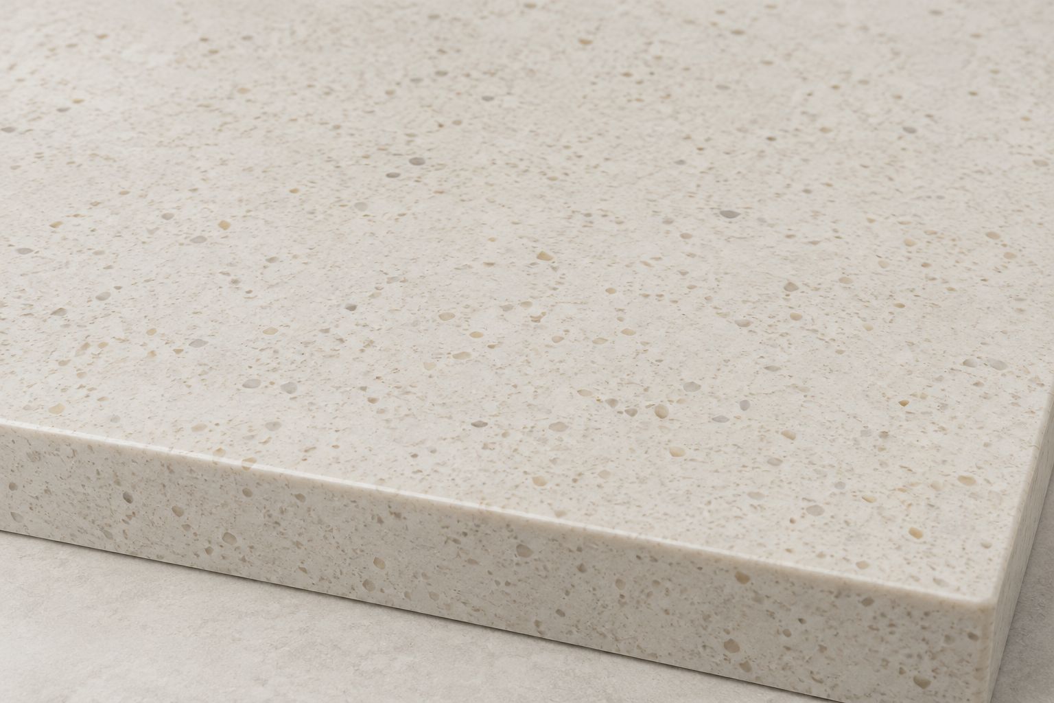 Ivory engineered quartz sample with fine beige flecks and an eased slab edge