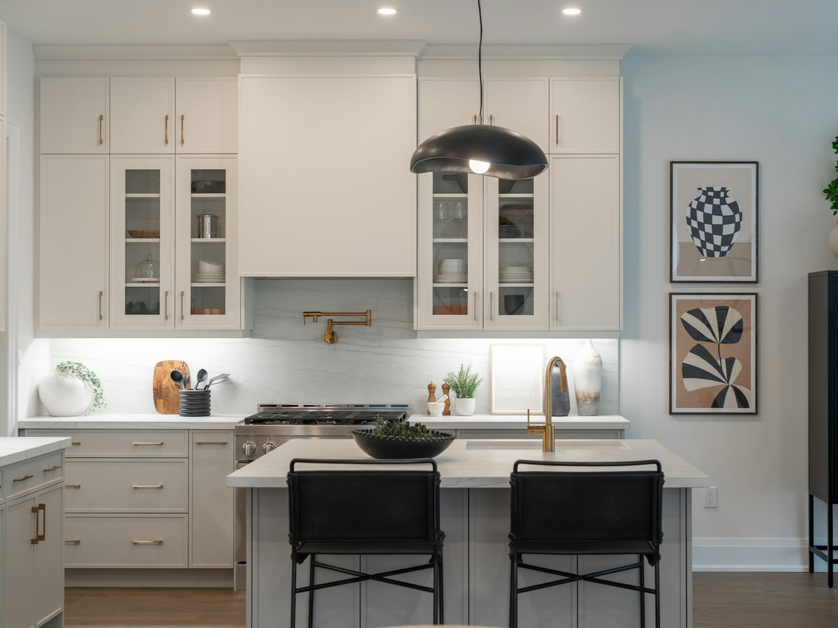 Under-cabinet lights illuminate the stone backsplash and worktop in a white kitchen